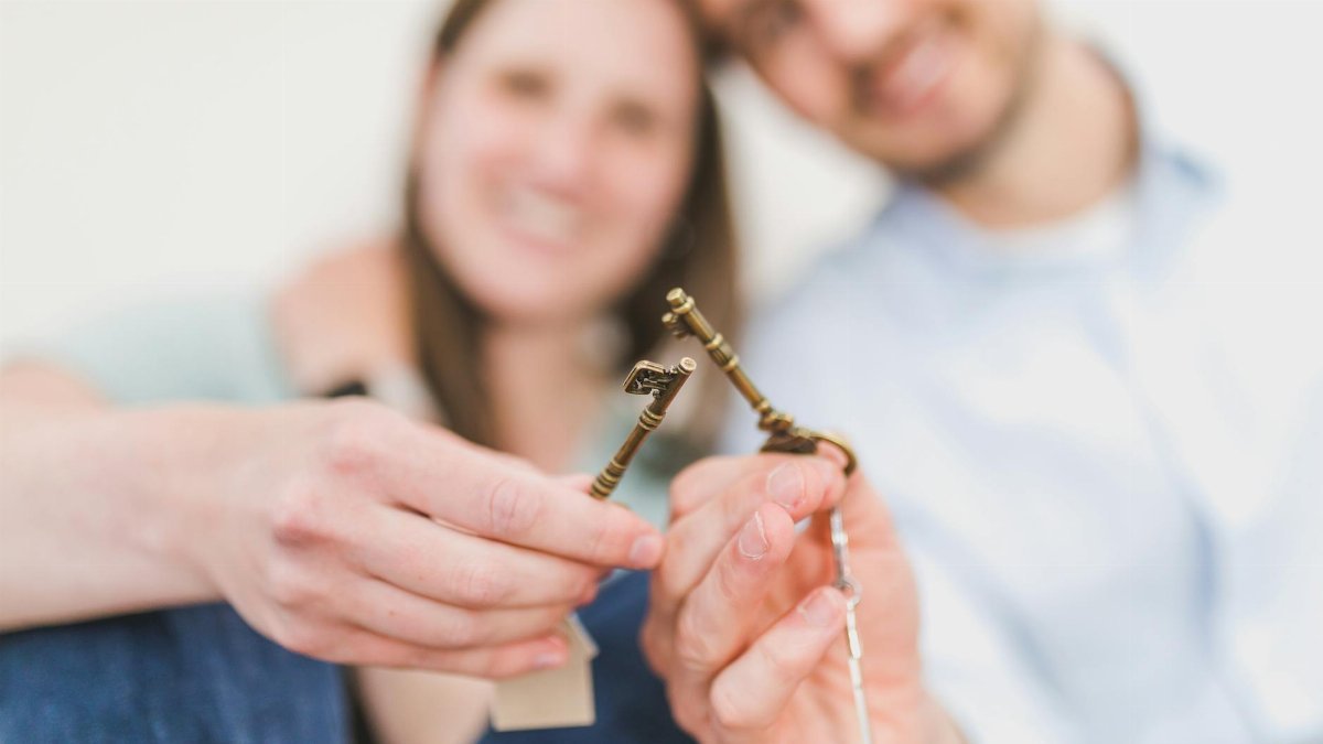 Smiling couple celebrates new home purchase, gripping vintage keys with love and excitement.