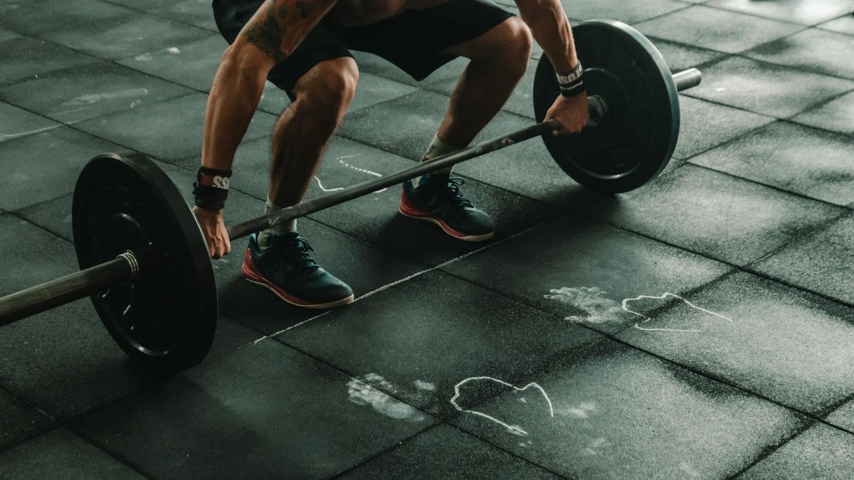 A muscular man in a gym preparing to lift a heavy barbell, showcasing strength and fitness.