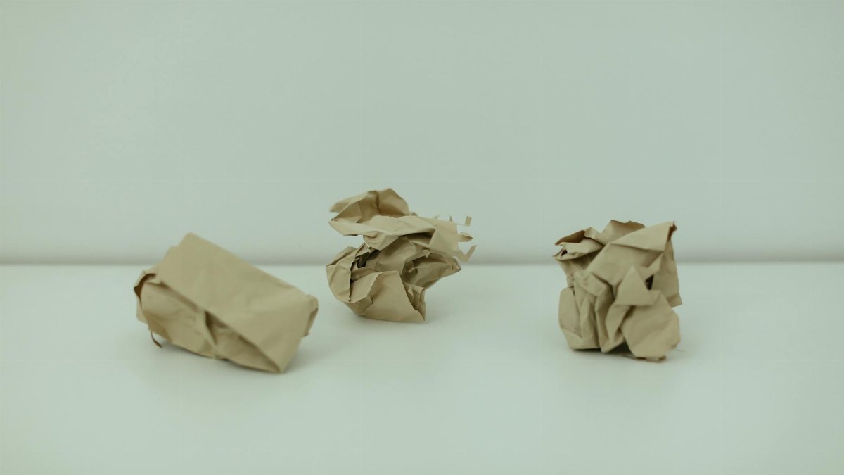 Minimalist image of three crumpled paper balls on a white surface, symbolizing burnout.