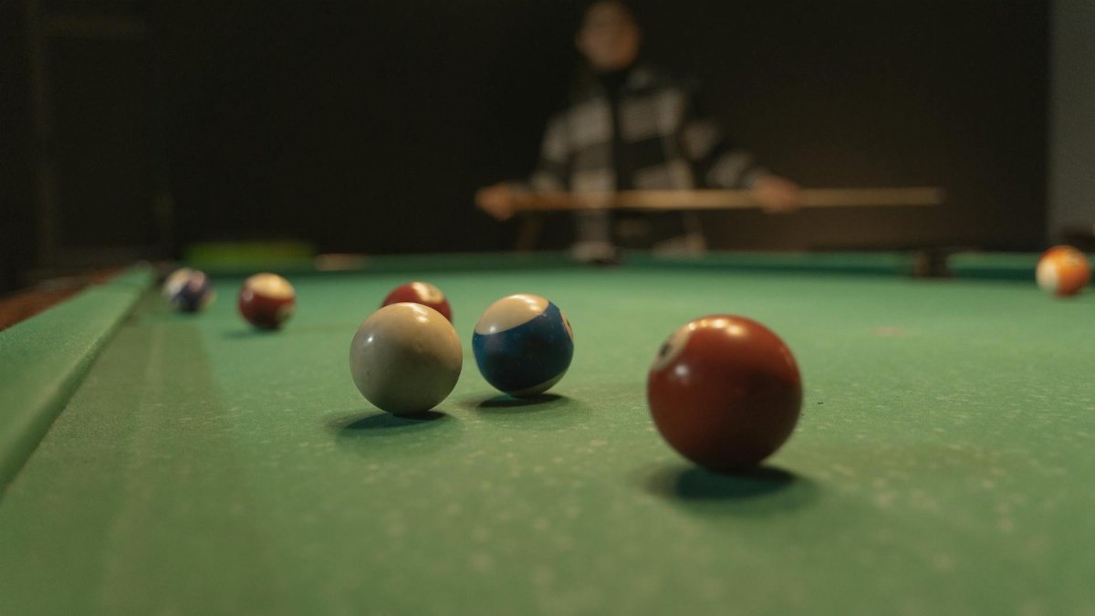 A vibrant shot of a billiards table with focused cue balls, capturing a player in the background.