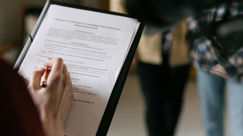 A couple examines real estate documents indoors with focus on writing and discussion.
