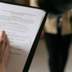 A couple examines real estate documents indoors with focus on writing and discussion.