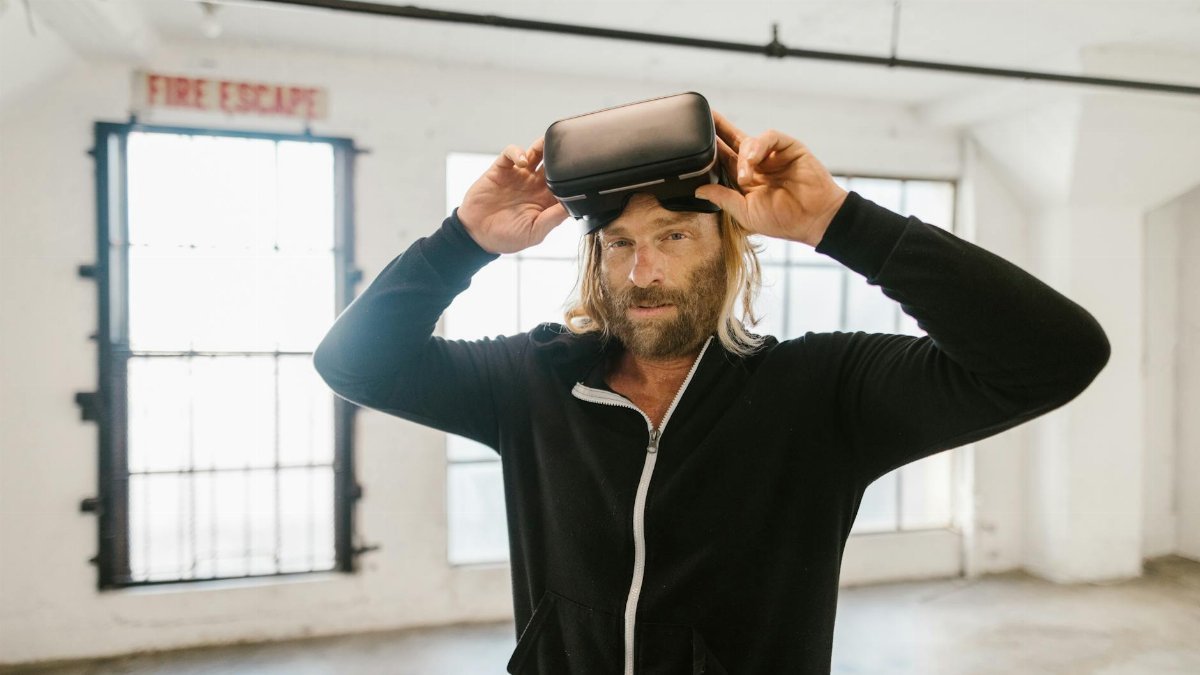 Man wearing a black jacket exploring virtual reality indoors with a headset.