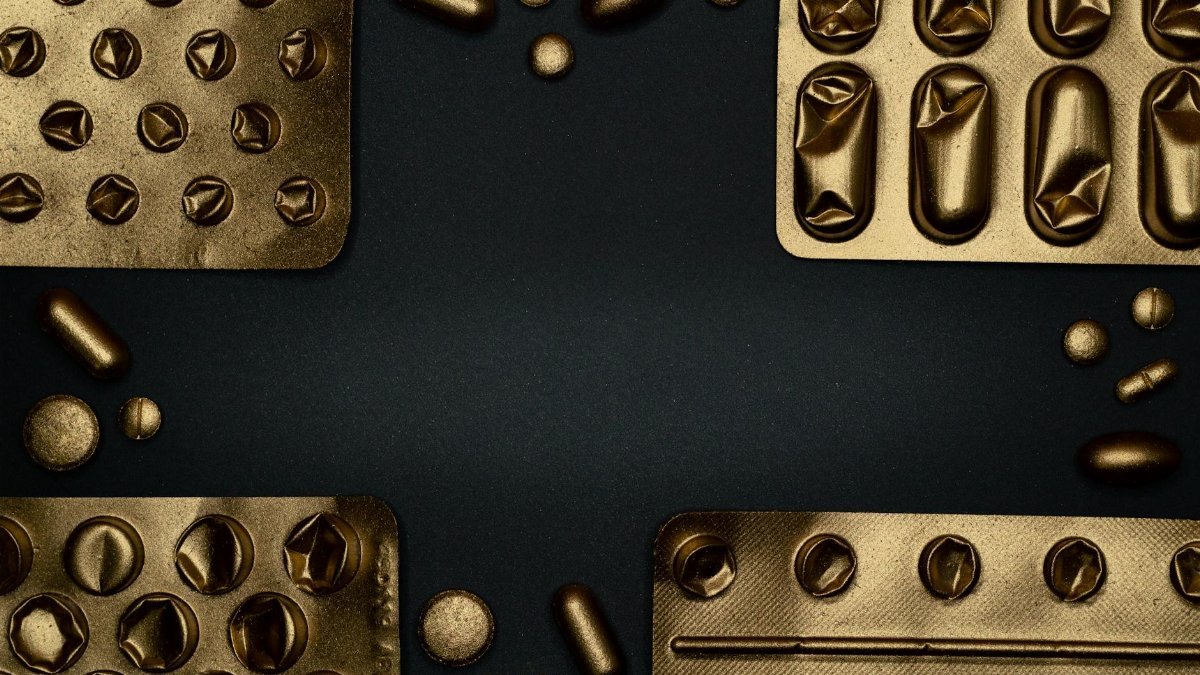 Close-up of metallic pills and blister packs on a dark surface, showcasing healthcare themes.