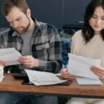 A couple reviewing financial documents at home, showcasing concern and focused collaboration.
