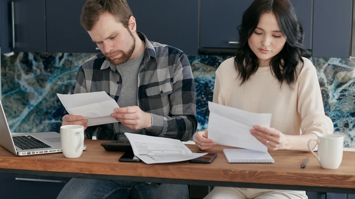 A couple reviewing financial documents at home, showcasing concern and focused collaboration.
