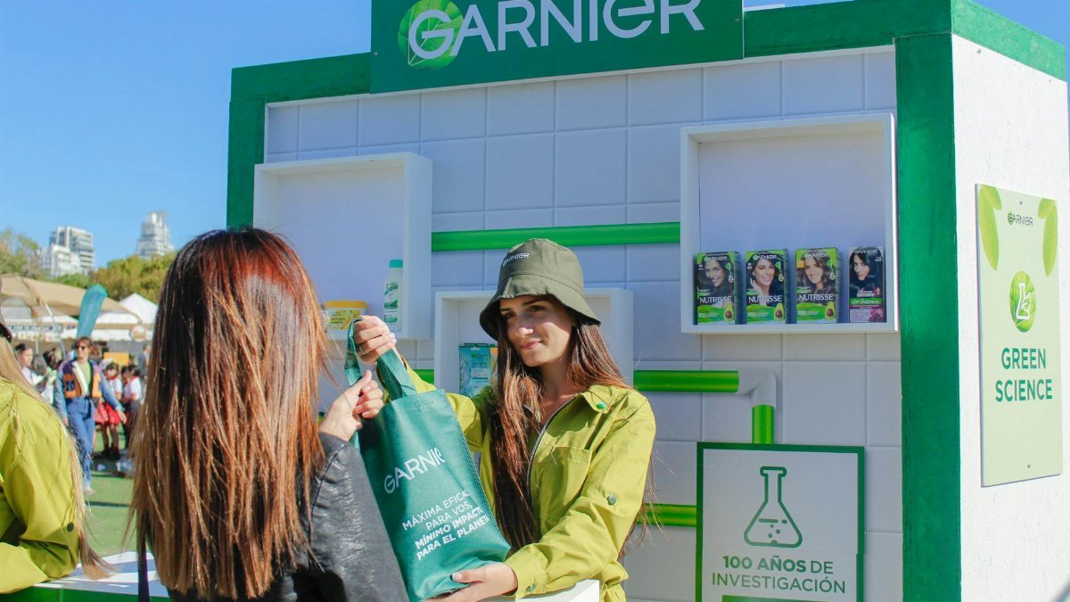 Garnier event with women distributing branded bags at an outdoor stall.