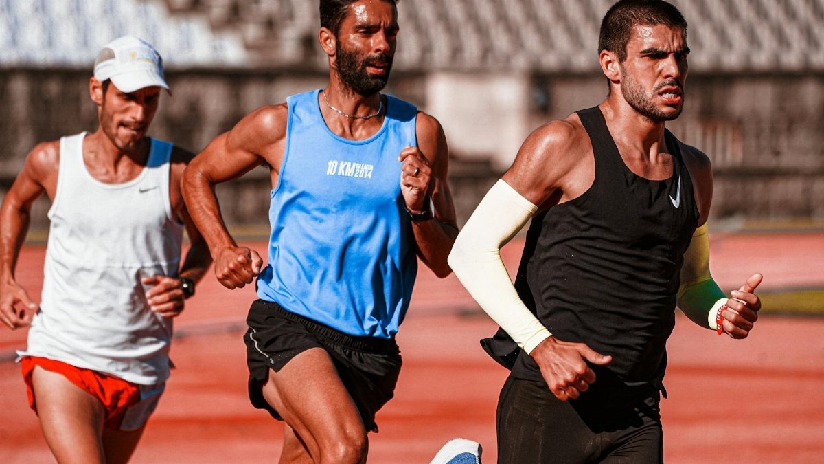 Three male athletes intensely focused on a track, captured mid-race showcasing their dedication.