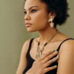 A stylish woman in elegant jewelry poses against a neutral background, exuding confidence.