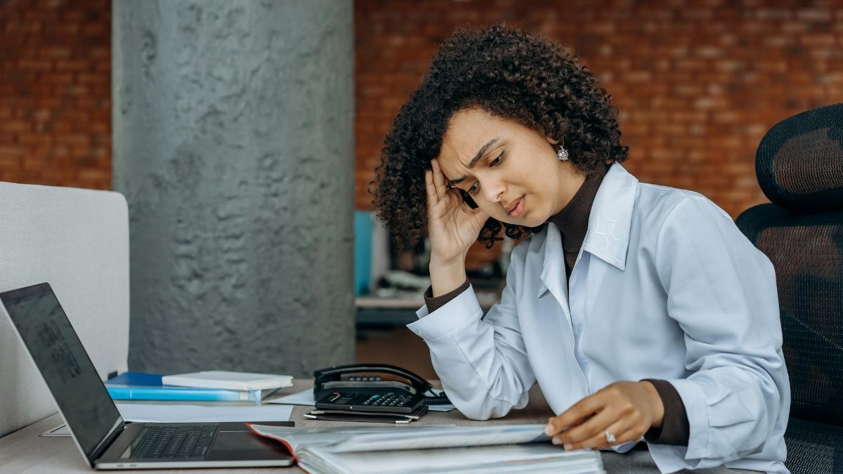 Businesswoman experiencing fatigue while working on financial paperwork at her desk.