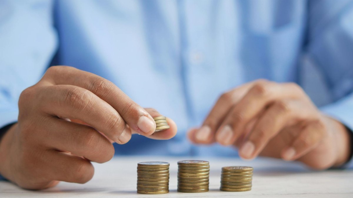 Close-up of hands stacking gold coins, symbolizing financial growth and savings.