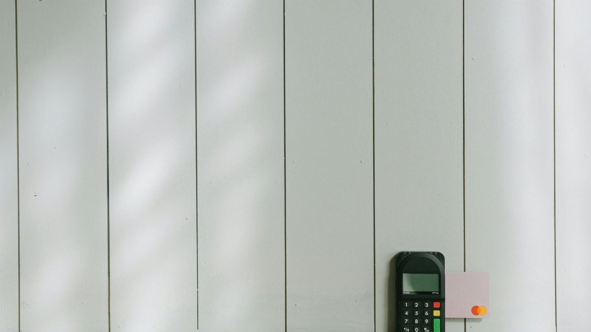 A sleek payment terminal with a card inserted against a light wooden background, showcasing modern commerce technology.