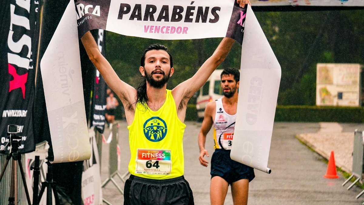 A triumphant male runner crosses the finish line in a marathon, capturing a moment of victory outdoors.