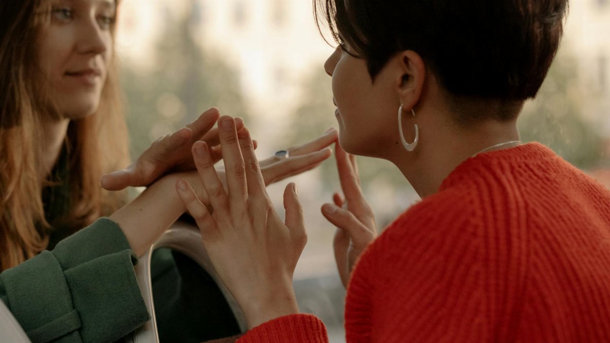 Two women share a tender moment, holding hands and making eye contact, expressing love and connection.
