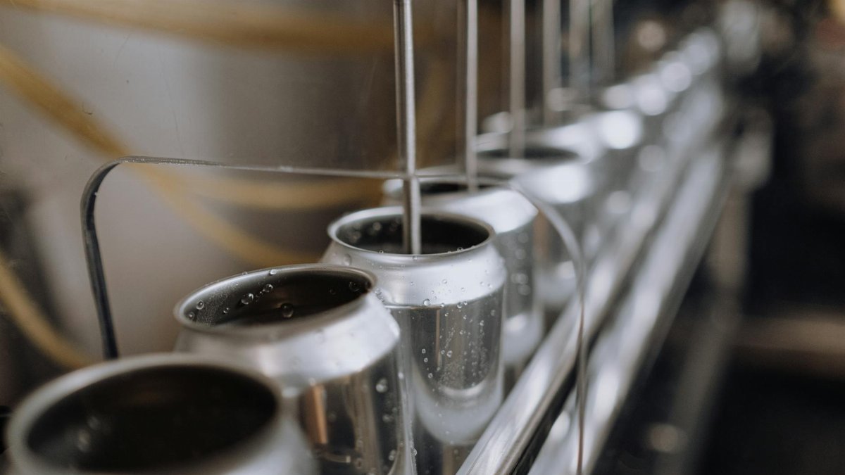 Detailed view of an industrial canning process with aluminum cans on an automatic assembly line.