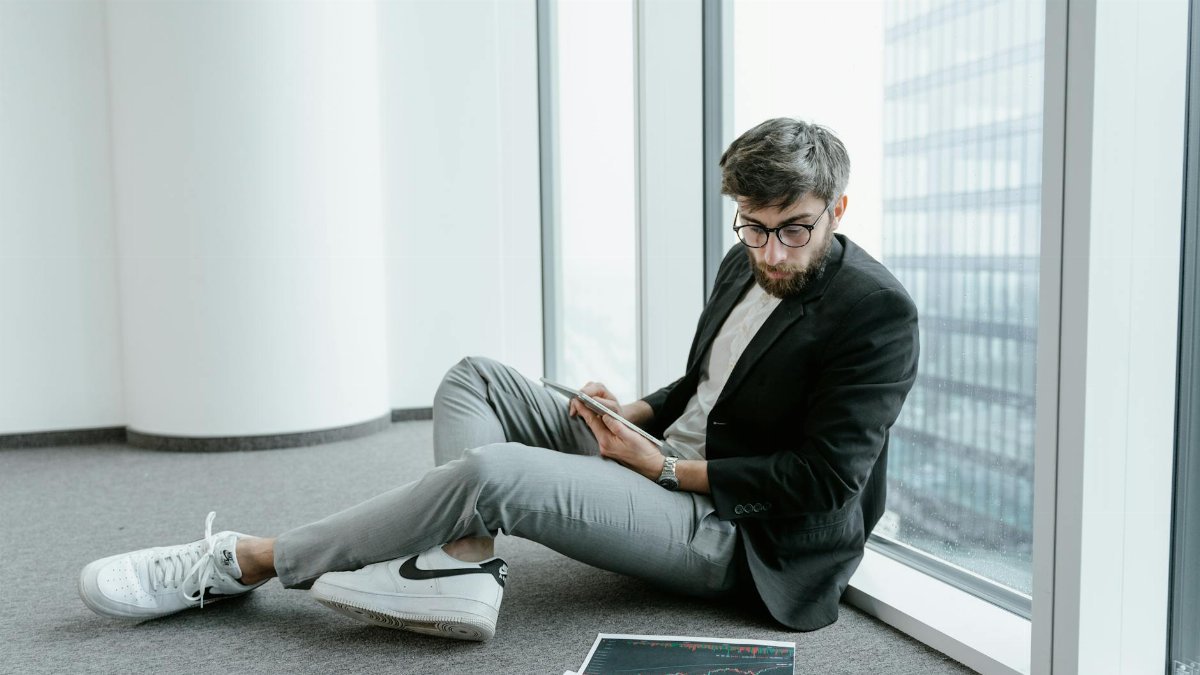 A man in an office setting using a tablet to analyze stock market data with graphs.