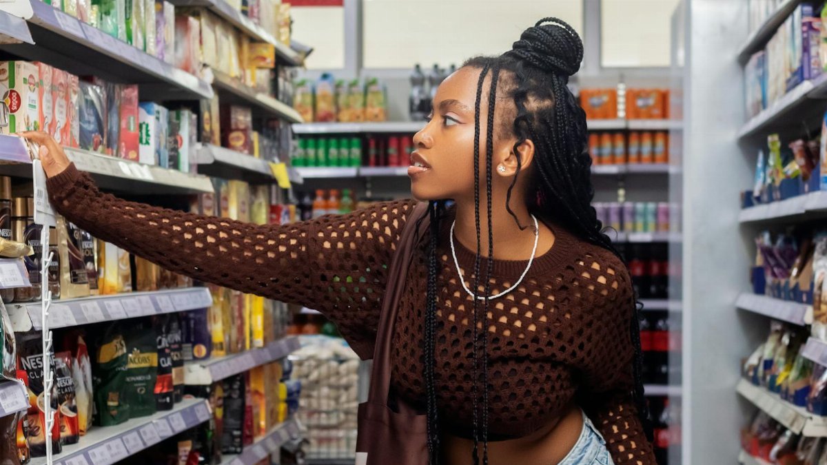 Fashionable young woman browsing products in a grocery store aisle.