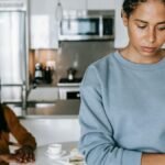 A couple in a kitchen experiencing a tense moment, reflecting on relationship issues.