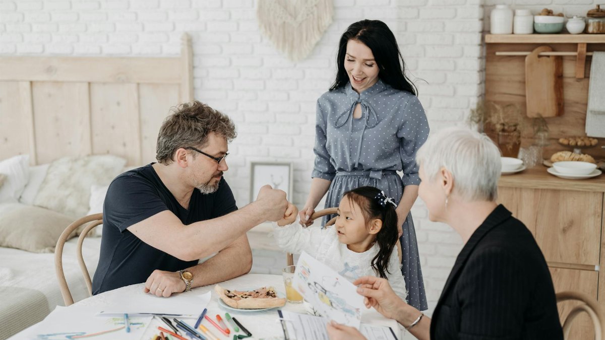 Child with foster parents and a social worker discussing adoption at home.