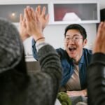 A diverse group of adults sharing a celebratory high five in a modern kitchen setting.