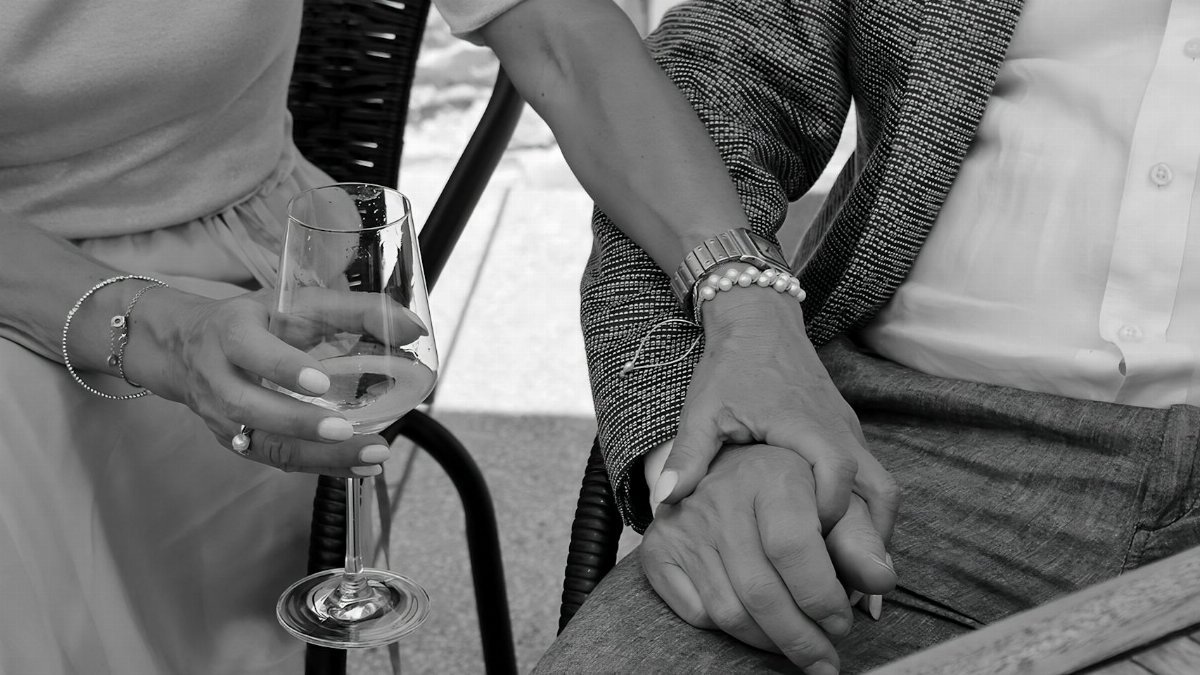 Close-up of a couple sharing an intimate moment, holding hands with a wine glass.