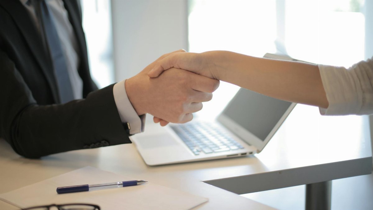 Close-up of a professional handshake over a laptop during a business meeting in an office.