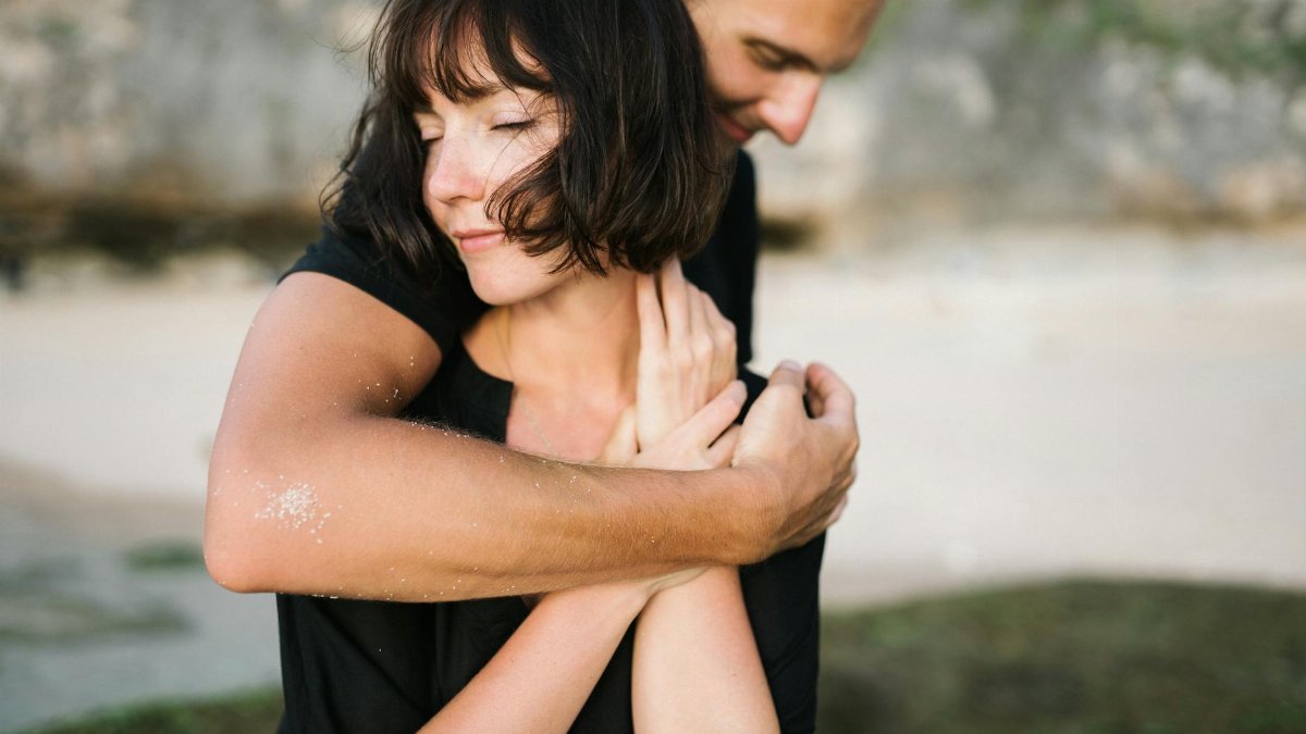 A couple embracing lovingly on a serene beach, capturing a moment of romance and connection.