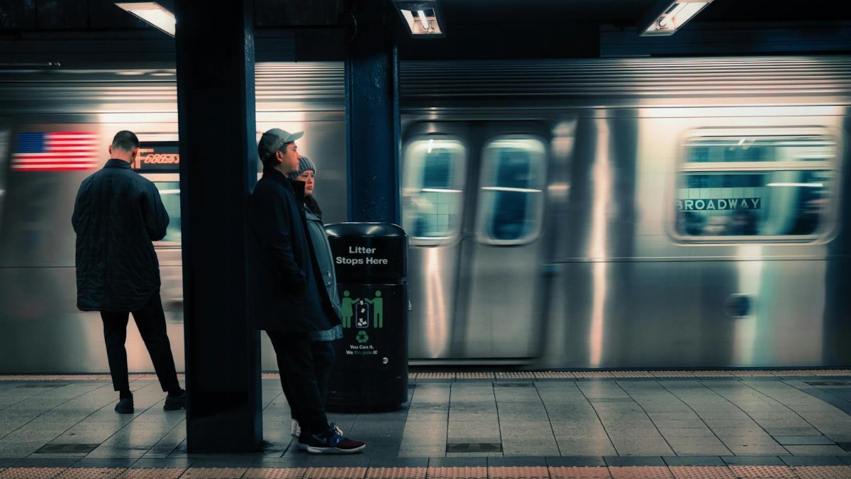 Blurred motion of train in New York subway station with waiting passengers.