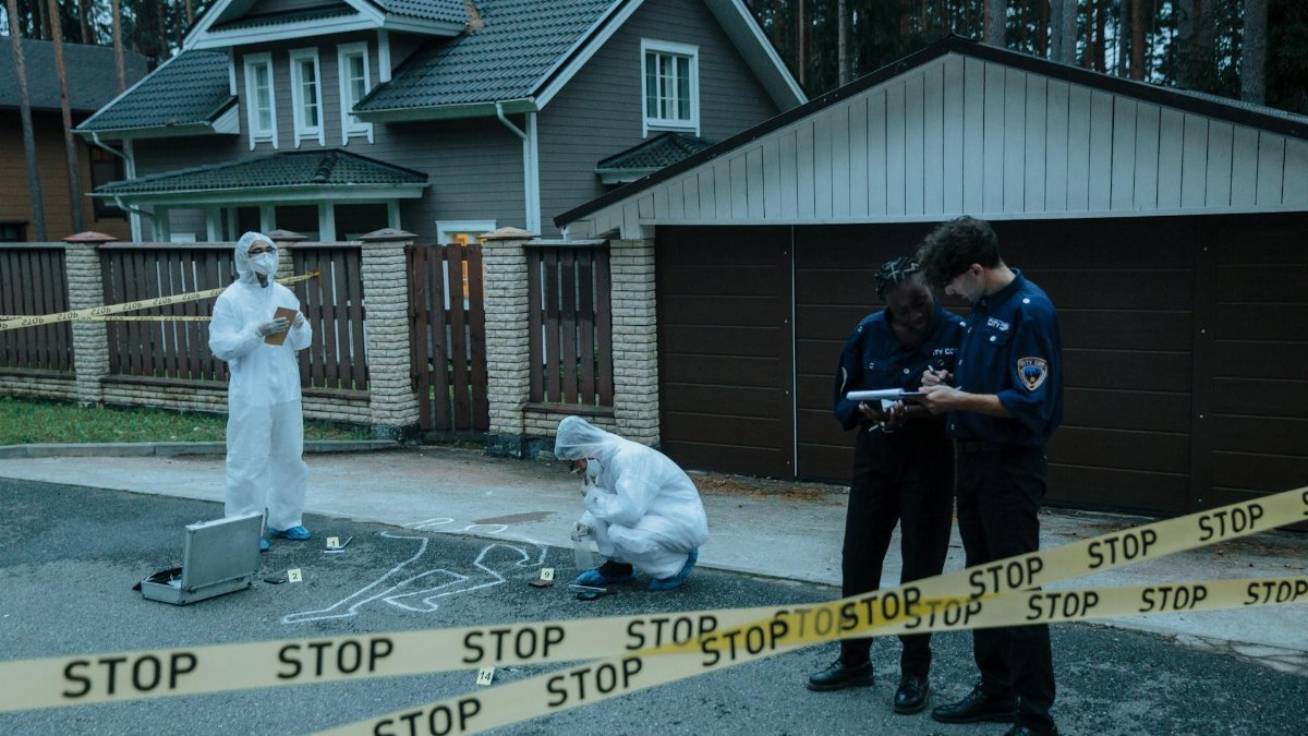 Forensic team investigates suburban crime scene with police officers and evidence markers.