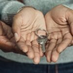 Close-up of a couple sharing a key, symbolizing new home ownership.