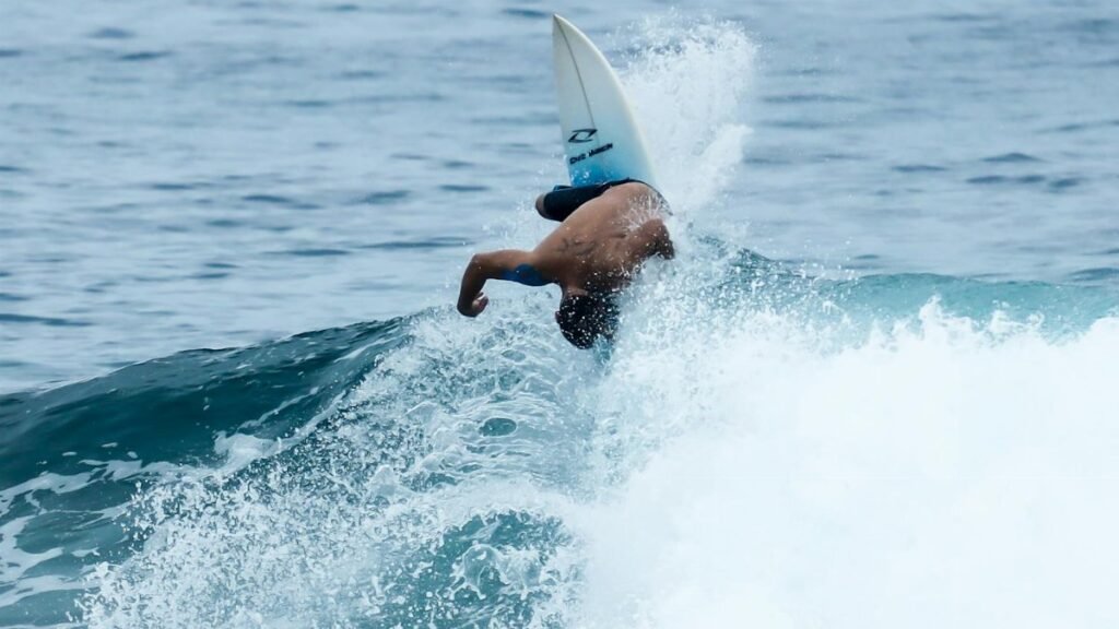 Surfer executing an acrobatic move on a wave in Brazil, showcasing skill and adventure.