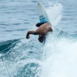 Surfer executing an acrobatic move on a wave in Brazil, showcasing skill and adventure.