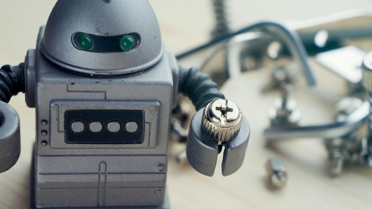 Detailed view of a toy robot holding a metallic screw, surrounded by tools.