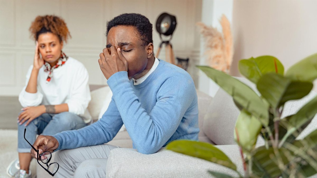 Man in blue sweater looking distressed during a therapy session indoors.