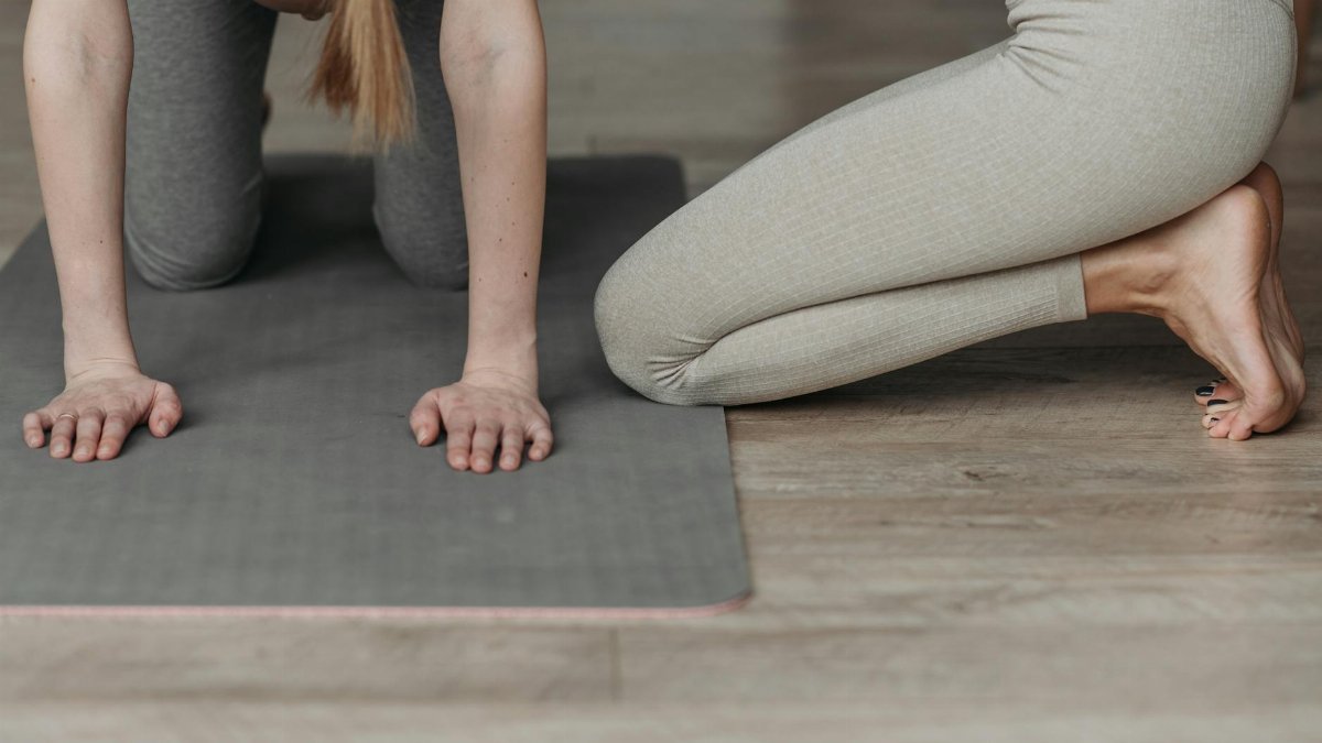 Pregnant woman on yoga mat engaging in prenatal exercise routine indoors.