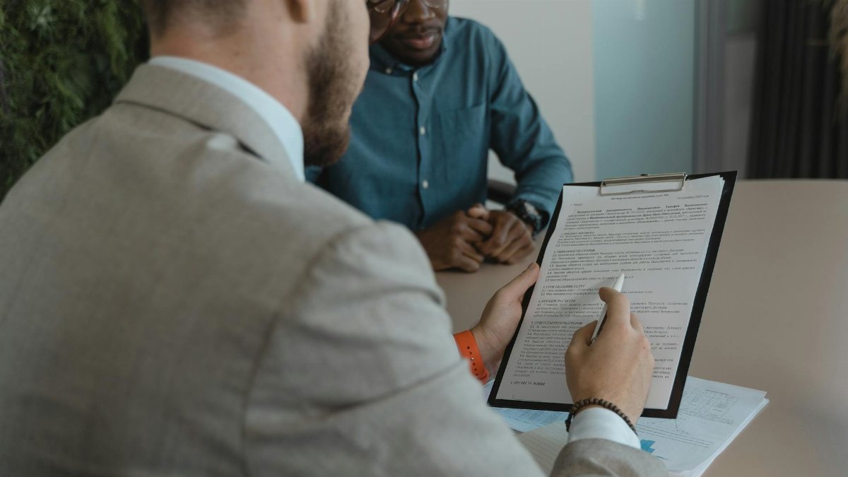 A recruiter reviews a candidate's documents during a job interview in a modern office setting.