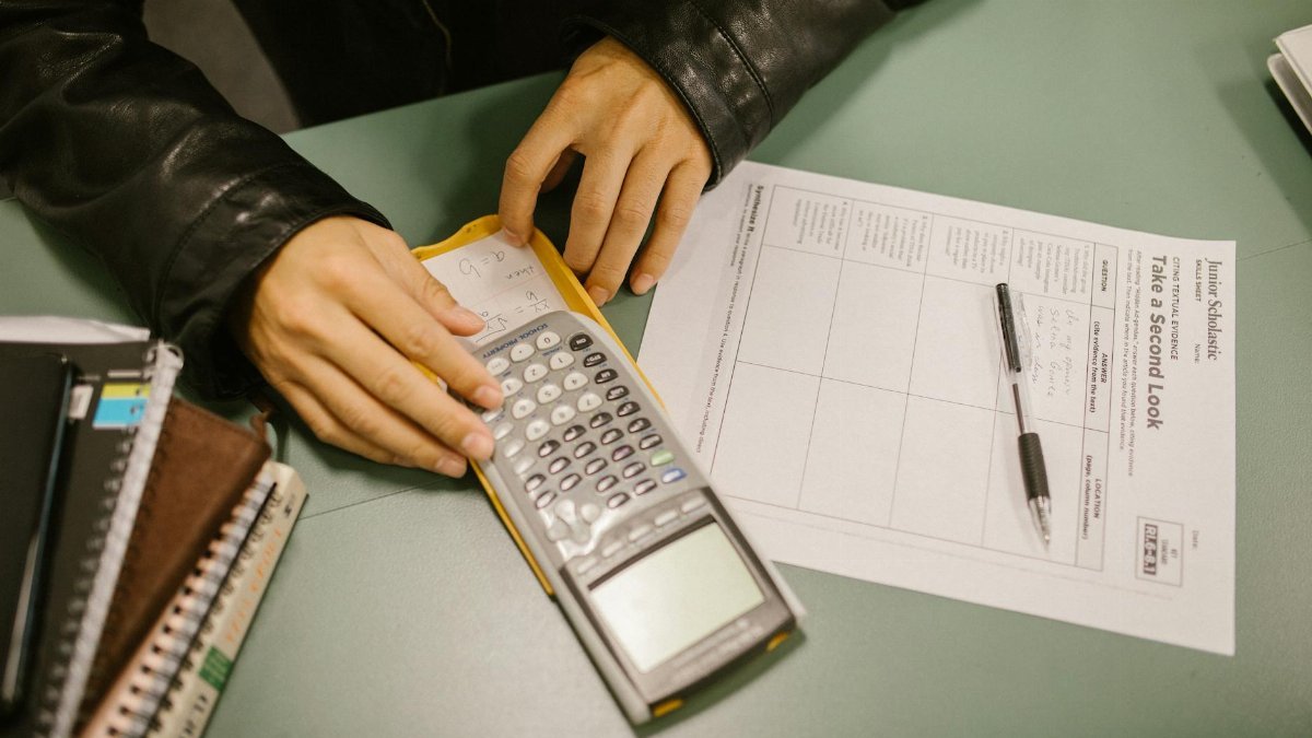 A student covertly uses a cheat sheet hidden in a calculator during an exam.