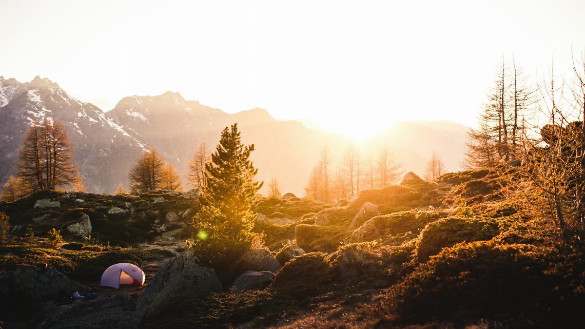 Captivating sunrise view over a tranquil Swiss mountain landscape with a distant tent.