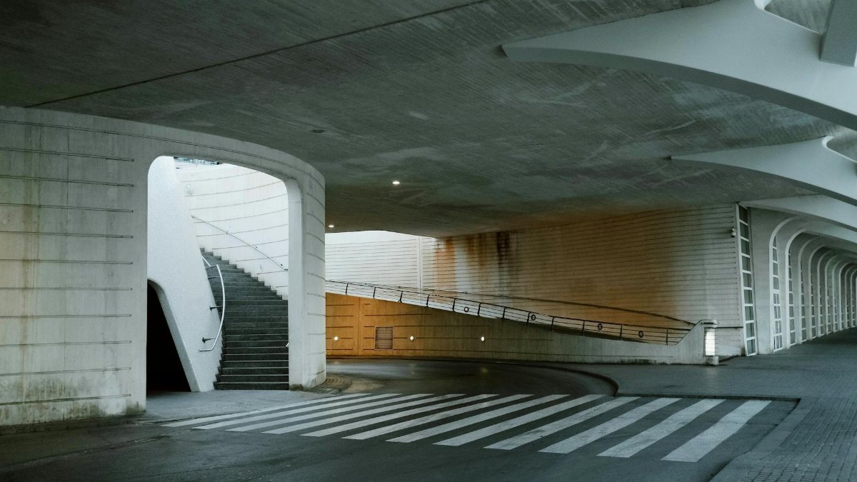 A modern underpass featuring a staircase, crosswalk, and architectural lighting in an urban setting.