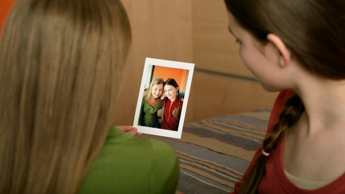Two teenage girls looking at an instant photo, sharing memories indoors.