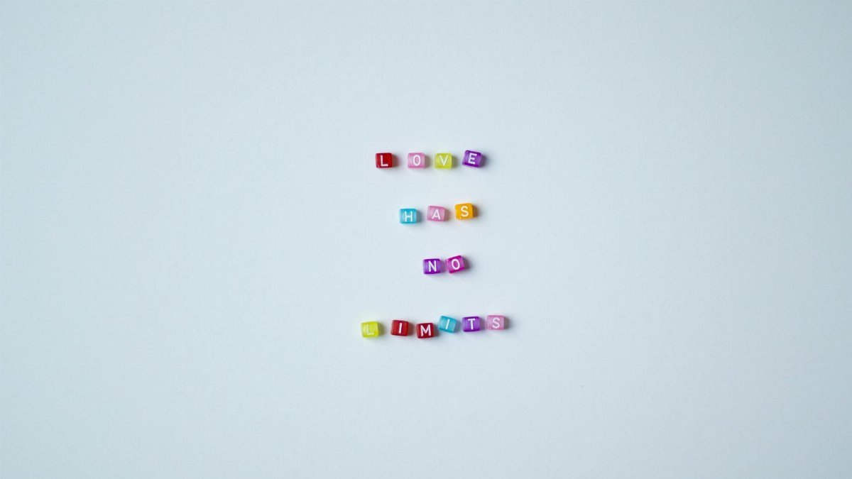 Vibrant bead letters spelling 'Love Has No Limits' on a gray background promoting inclusivity.