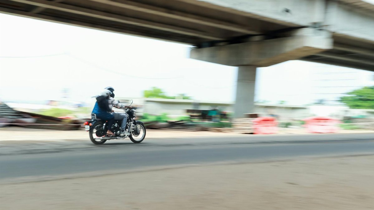 A motorcycle rider speeds under a bridge in Kochi, capturing the essence of urban motion.