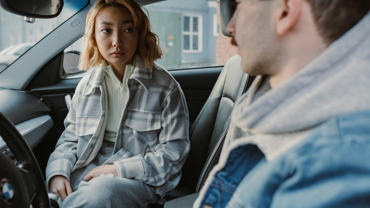 A young couple engaged in a serious conversation inside a parked car, capturing emotional tension.