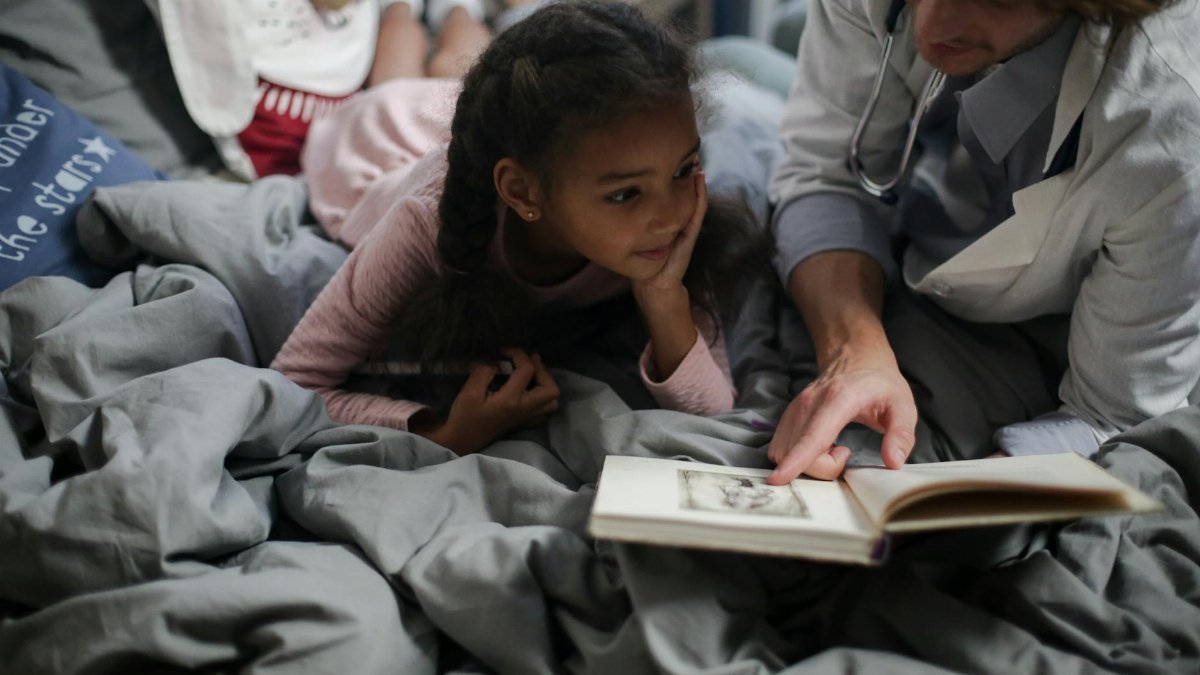 A father and daughter enjoy quality time reading a book together in a cozy setting.