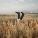 Playful image of legs in boots emerging from a wheat field at sunrise in a rural setting.