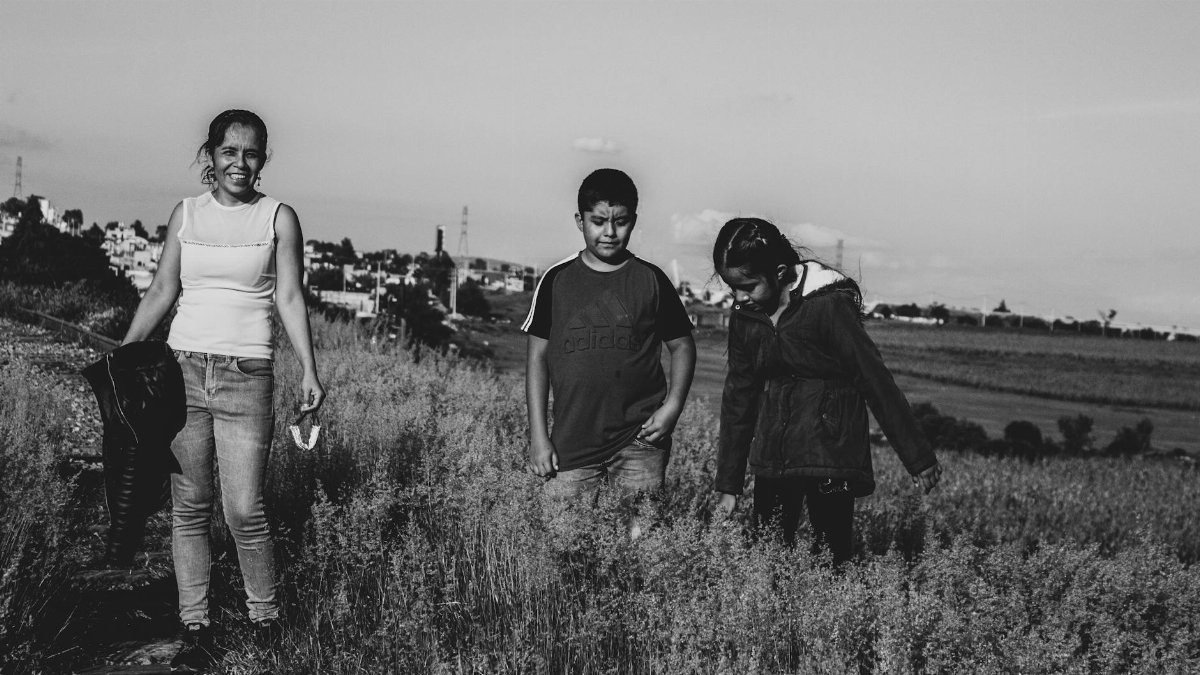 A mother and two children walk through rustic fields, capturing family bonds and rural life.