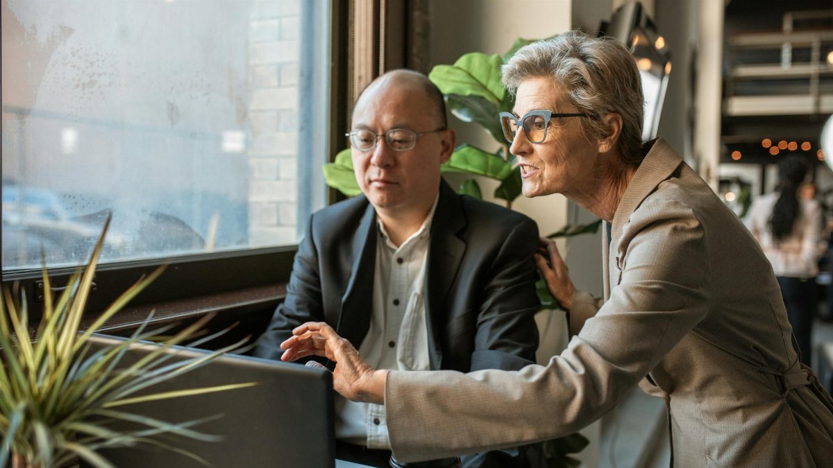 Senior professionals discussing a project at a modern office workspace.