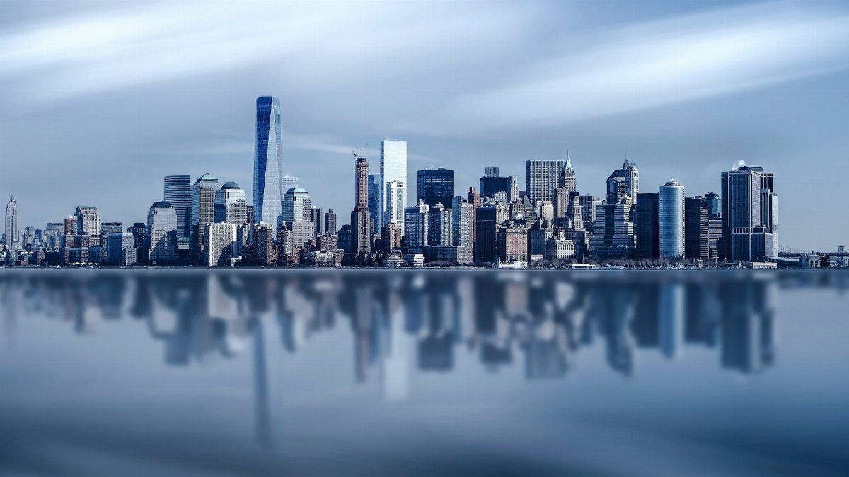 Stunning New York City skyline with modern skyscrapers reflecting on a calm river.