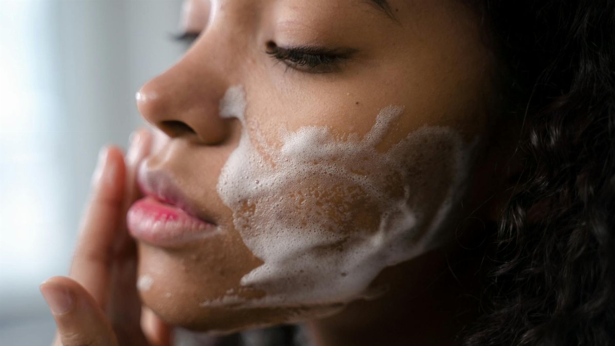 A woman applies skincare foam to her face for a gentle cleansing routine.
