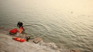 A man washing clothes by the river in Varanasi at sunset, showcasing traditional lifestyle.